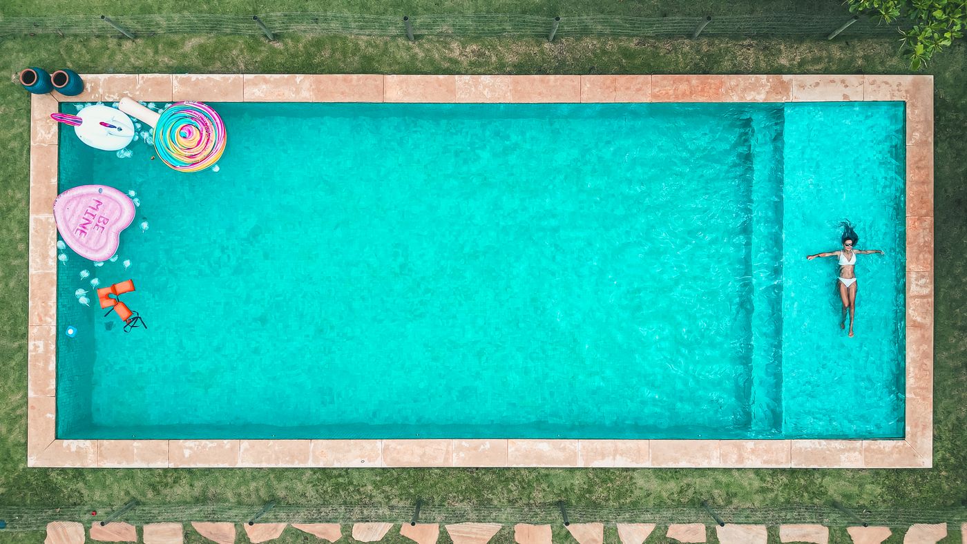 Piscine turquoise vue du ciel avec bou&eacute;es, h&ocirc;tel familial